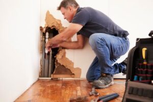middle aged man repairing burst water pipes