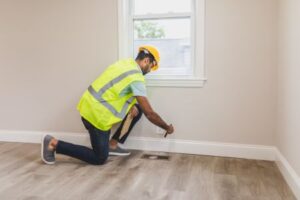 man wearing yellow safety vest and helmet checking the floor of the house