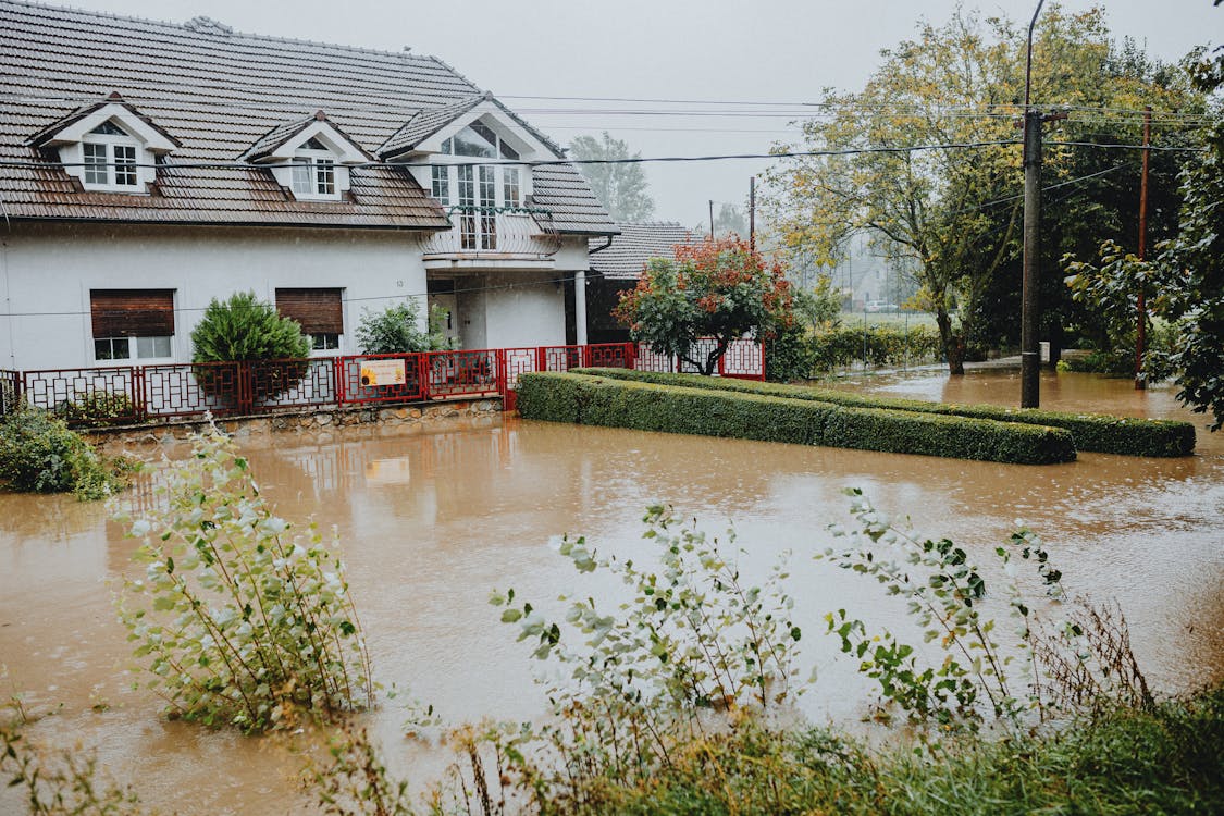Floodwater surrounding a suburban home after heavy rain, showing the need for emergency water damage restoration in the Dallas-Fort Worth area.
