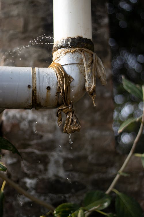 Leaking PVC pipe spraying water from a damaged joint, creating a risk of water damage that may require emergency water cleanup in Dallas-Fort Worth.