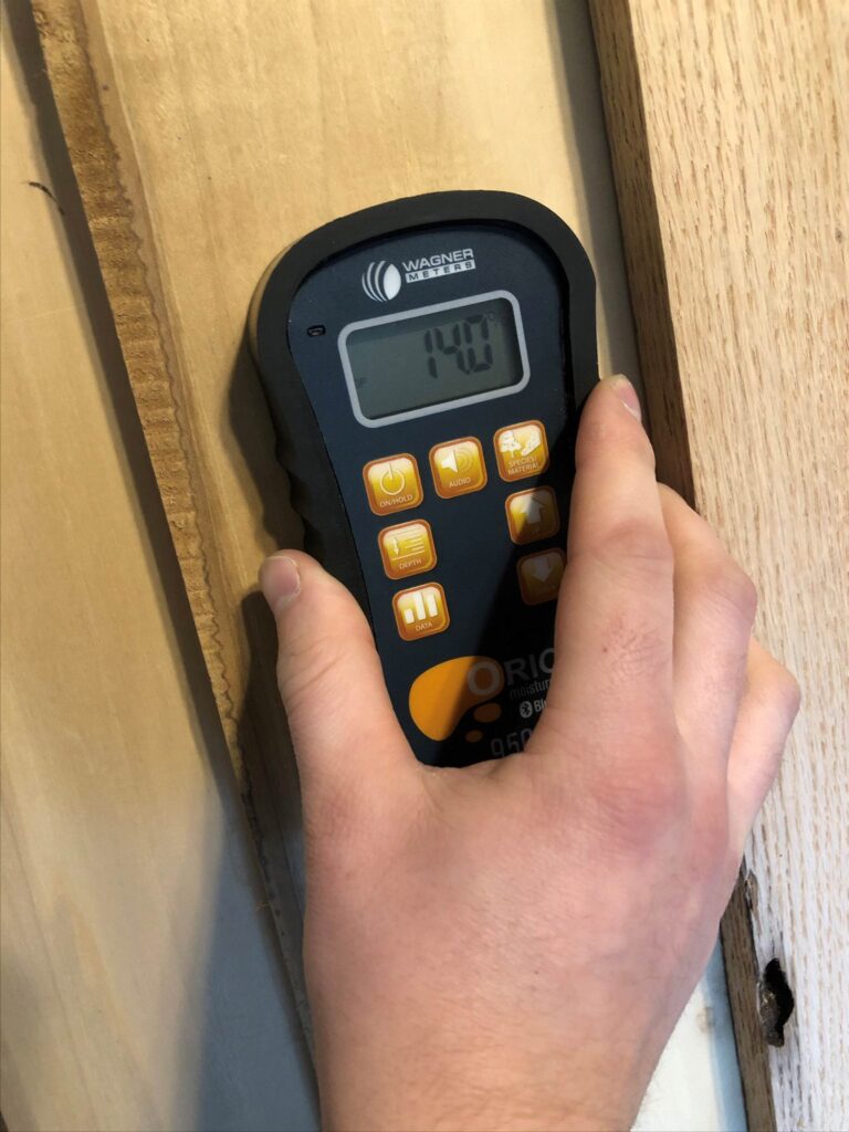 Technician using a moisture meter on wood trim to check hidden moisture after water damage in a Dallas-Fort Worth property.