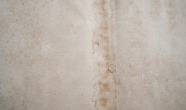 Brown water stain on a white interior wall indicating water damage from a leak above — the most common visible sign that an AC condensate drain line has been overflowing into ceiling drywall