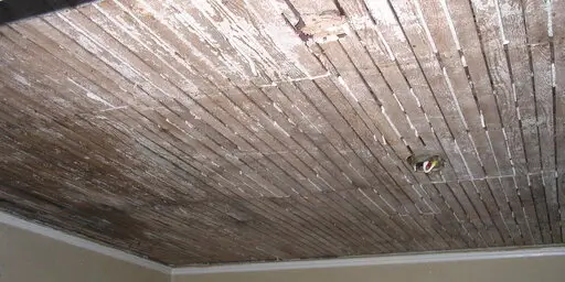 Water-stained wood slat ceiling with visible moisture damage and discoloration caused by an HVAC leak.