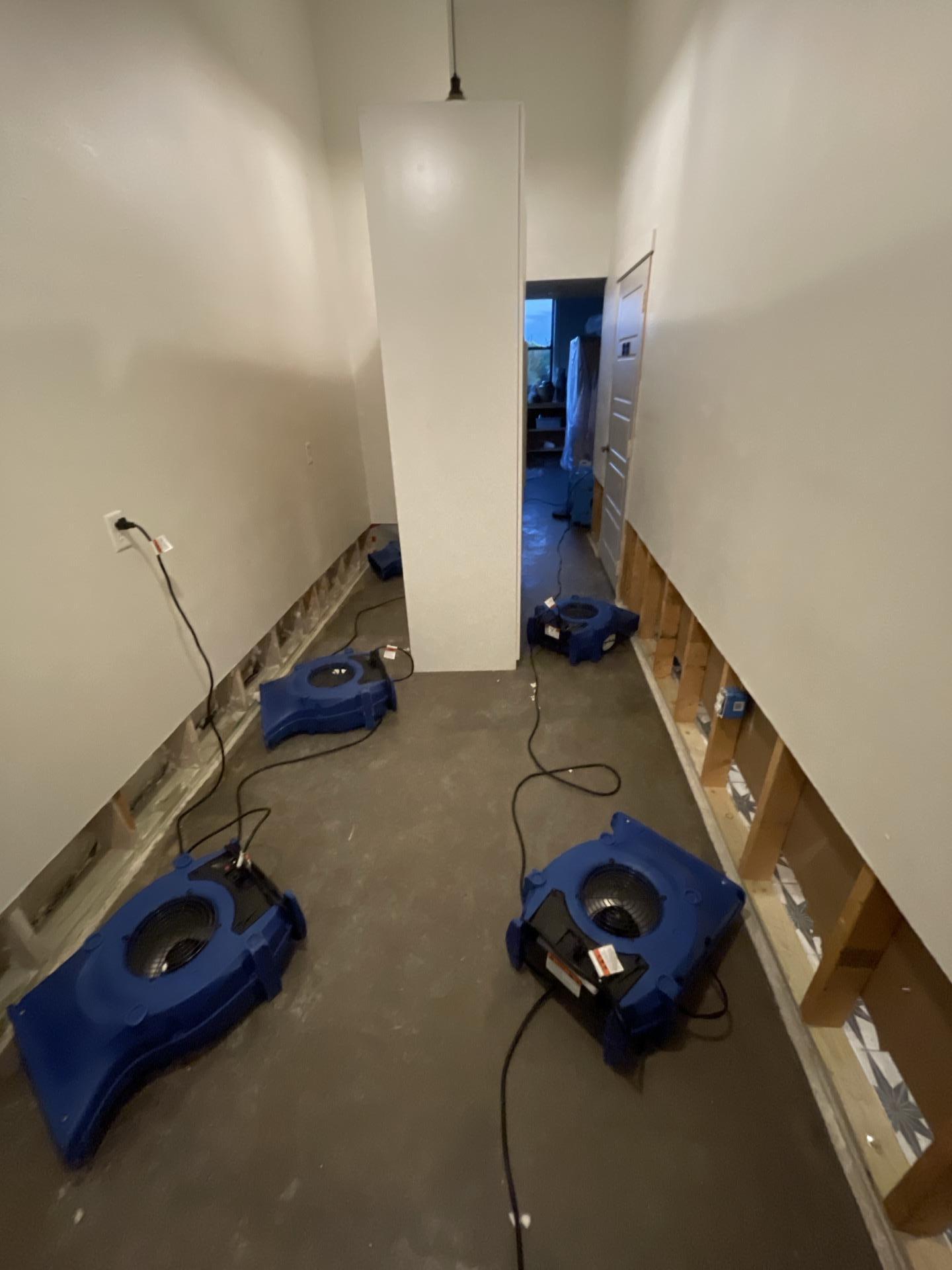 Air movers and dehumidifier drying a hallway with drywall flood cuts