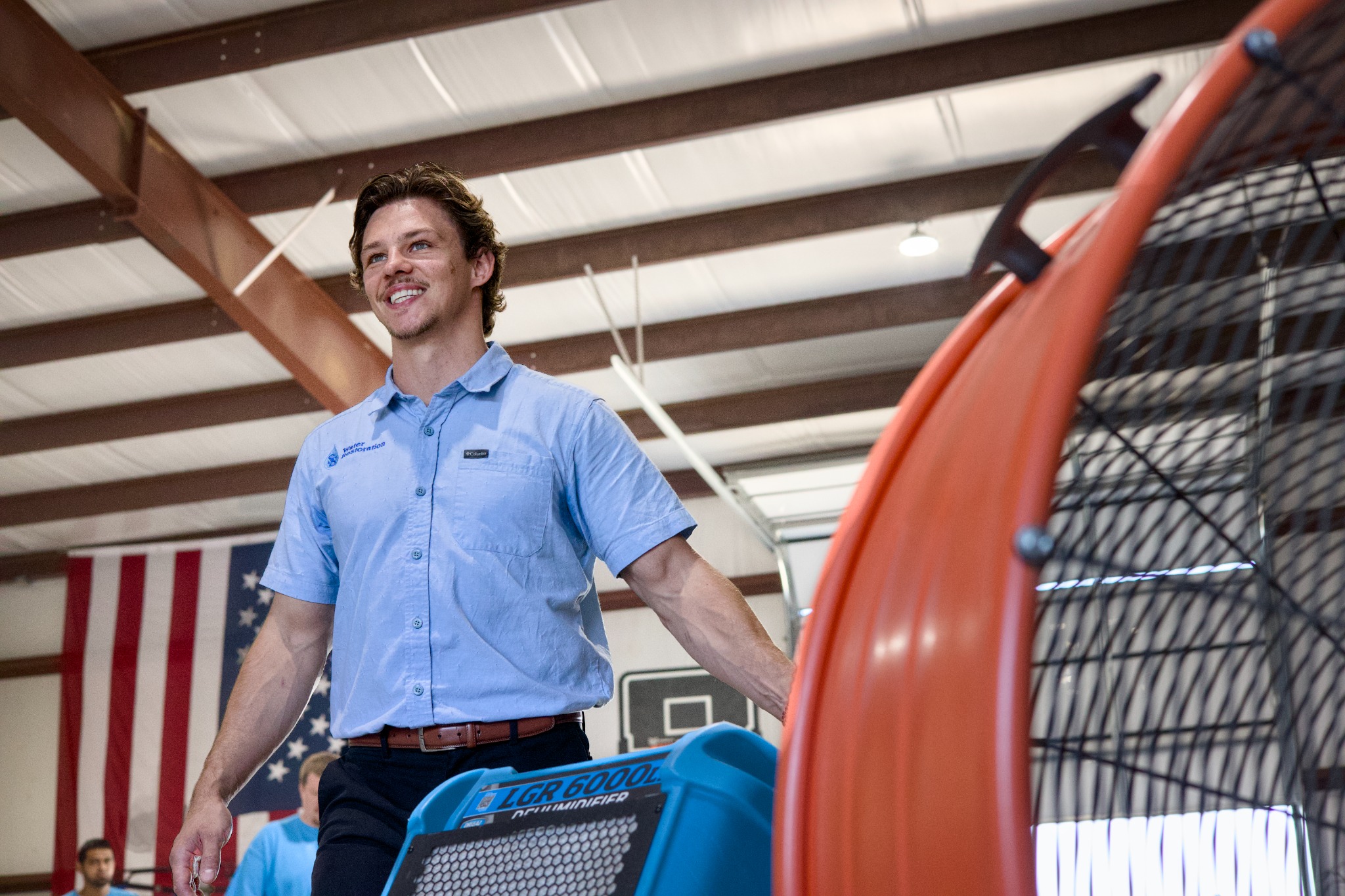 SS Water Restoration technician with an air mover in the warehouse